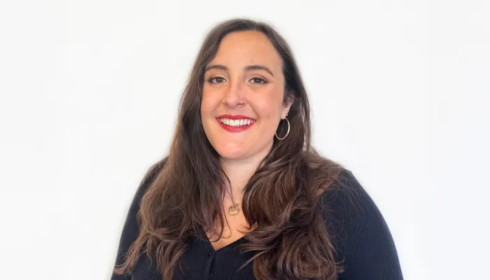 Ellie smiling at the camera, with long dark hair and wearing a black top.