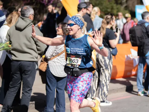A woman smiling and running with a CCLG-branded t-shirt