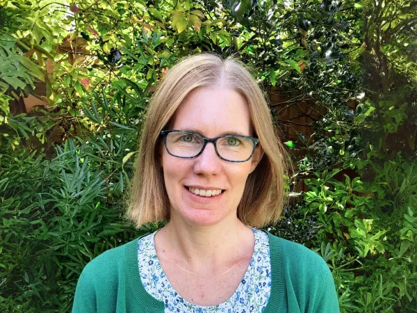 Susie outdoors, smiling at the camera in a green cardigan and floral blouse.