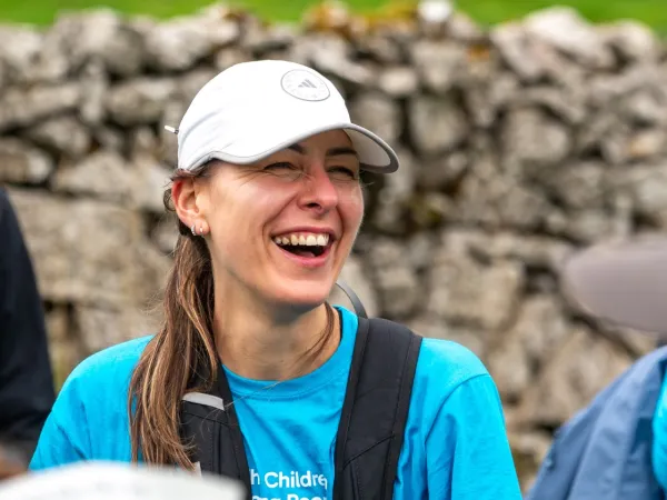 A smiling woman wearing a white cap and a teal CCLG t-shirt whilst on the Big Hike