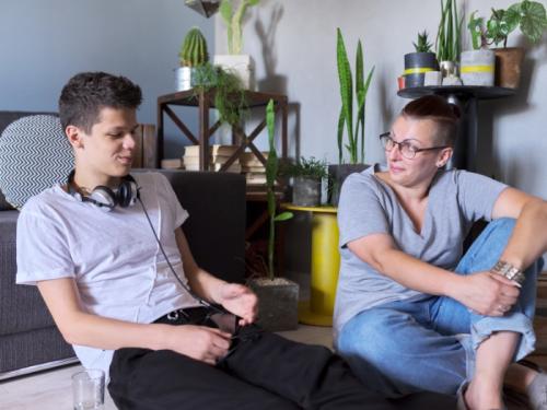 A young man sitting in a living room and talking to his mother