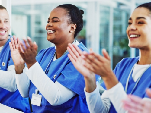 three different and diverse nurses clapping wearing blue uniform