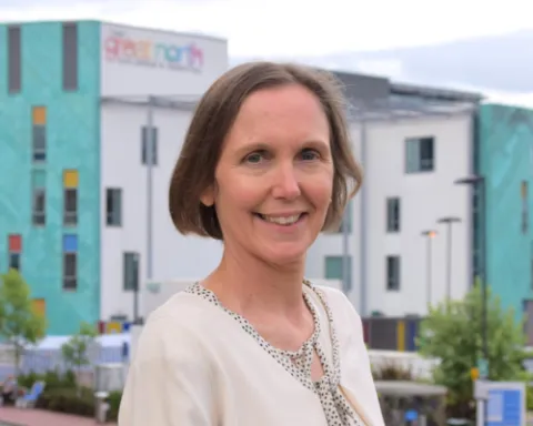 Deborah smiling at the camera. She has short brown hair and is wearing a light coloured blouse.
