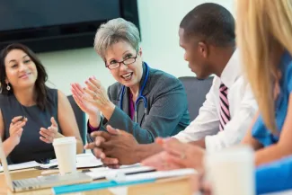 A group of doctors are having a discussion whilst sitting around a table.