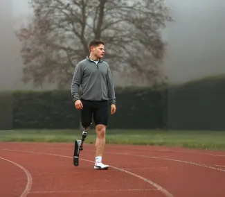 A young man with a prosthetic leg is standing on a running race track.