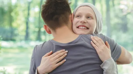 A young girl with a headscarf, smiling and hugging a young boy
