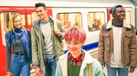 A diverse group of young adults smiling in front of a subway train