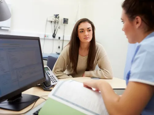 A nurse consulting a young woman in her office.
