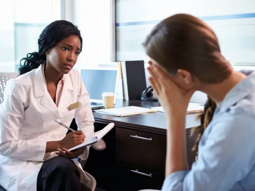 A young woman looking emotional while talking to her doctor.
