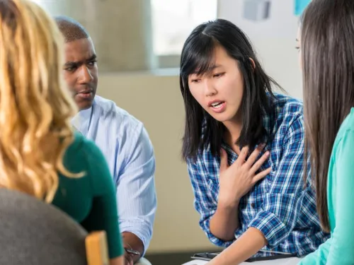 A young woman is talking about her personal experience to a group.