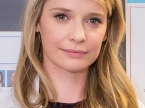 Laura smiling at the camera with long blonde hair and wearing a white lab coat.