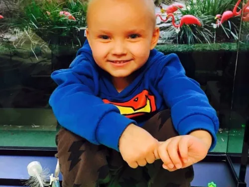 Kai Nell, sat in front of an aquarium and wearing a blue superman hoody.