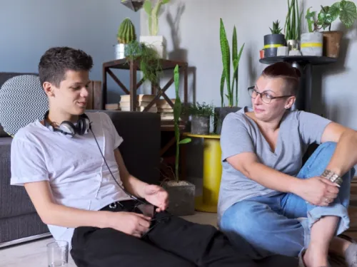A young man sitting in a living room and talking to his mother