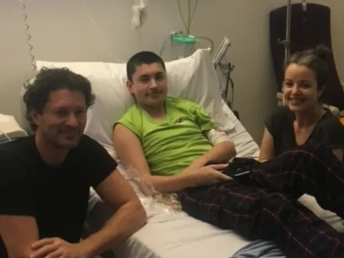 Dad, mum and son sitting in a cancer warn on a hospital bed 